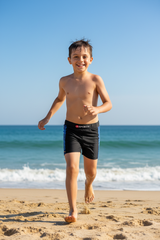 Boy running on beach wearing Konexpro black blue bubble swim shorts